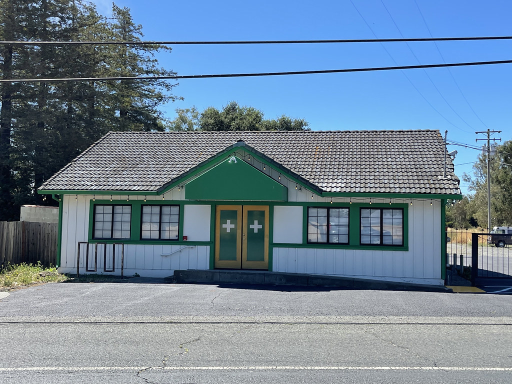 Small cannabis dispensary building with green trim
